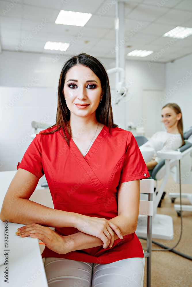 Fototapeta premium smart charming woman dentist sitting on computer desk, smile and looking at camera