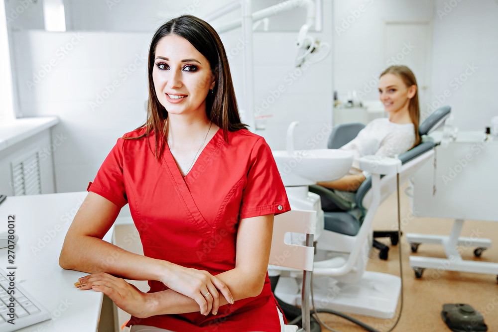 Obraz premium smart charming woman dentist sitting on computer desk, smile and looking at camera