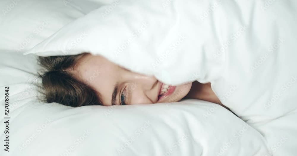 Close up of happy woman smiling and having fun in the bed while waking up in sunny bedroom Close up of happy woman smiling and having fun in the bed while waking up in sunny bedroom