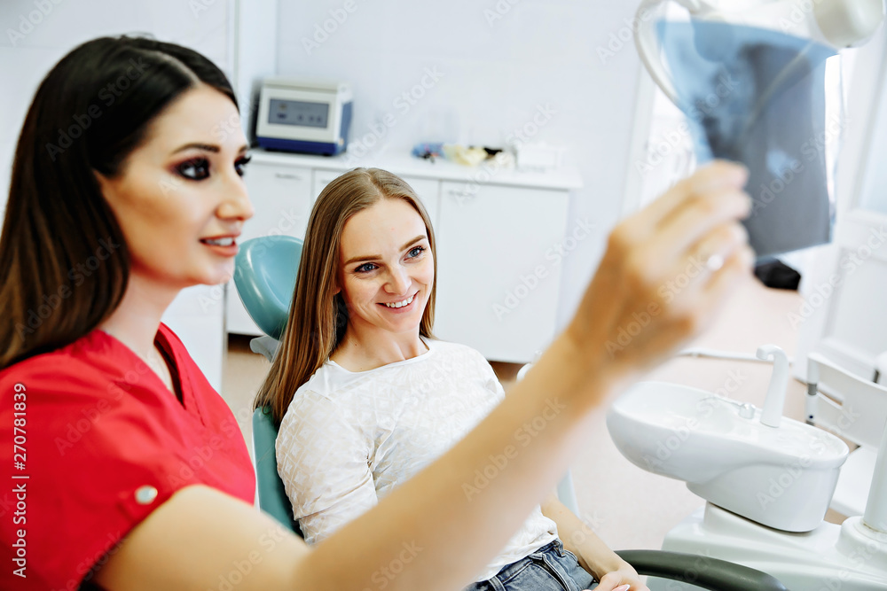Dentist showing X-ray image to patient. People, medicine, stomatology, technology and health care concept Dentist showing X-ray image to patient. People, medicine, stomatology, technology and health care concept