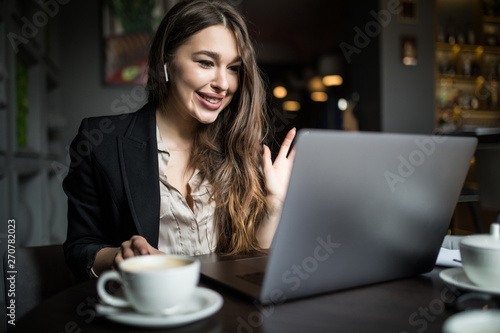 Beautiful young woman working with laptop in a cafe.