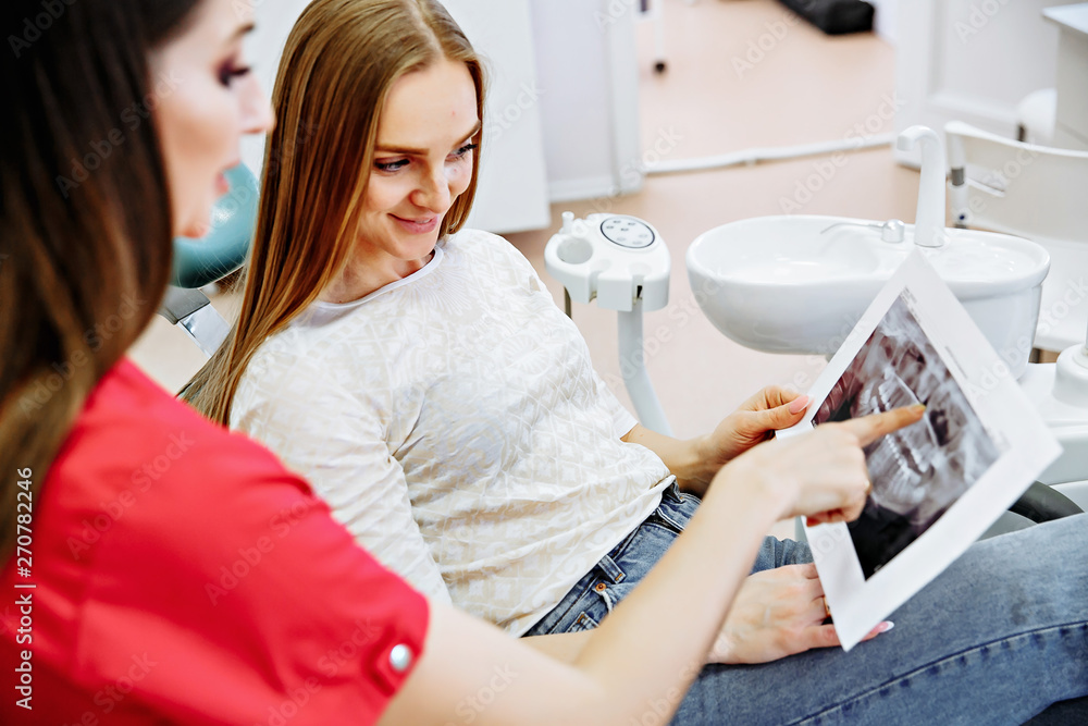Dentist showing X-ray image to patient. People, medicine, stomatology, technology and health care concept