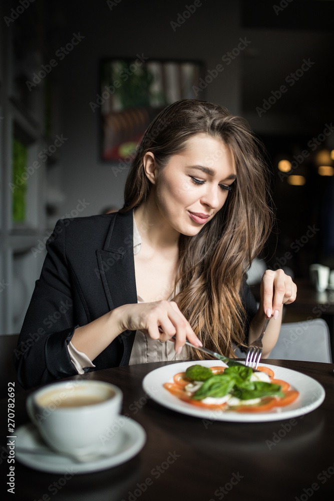 Smiling young woman eating fresh salad in restaurant Smiling young woman eating fresh salad in restaurant