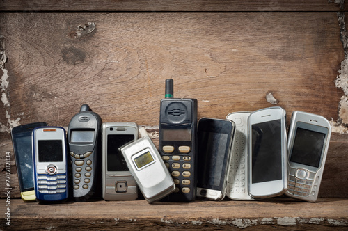 Old and obsolete mobile phone or cell phones on space of old wood background