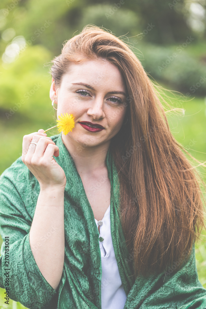 Frau, jung, 20-30, lächelnd, romantisch, genießt die ersten Sonnenstrahlen im Frühling und hält einen Löwenzahn in der Hand. Frau, jung, 20-30, lächelnd, romantisch, genießt die ersten Sonnenstrahlen im Frühling und hält einen Löwenzahn in der Hand.