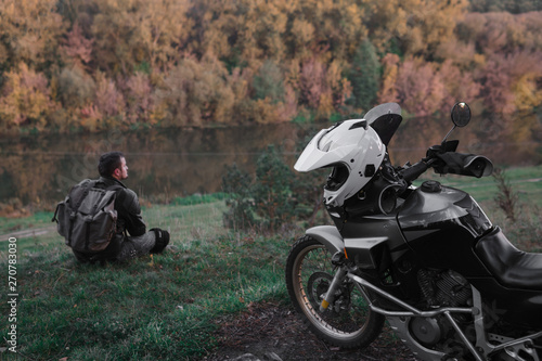 Lonley concept, man is sitting alone and look at the distance. Adventure motorcycle, Motorcyclist, A motorbike driver looks, concept of active lifestyle, enduro travel road trip, destination