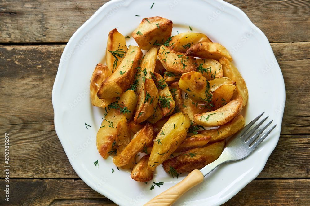 Baked potato slices with fresh dill on a white plate Baked potato slices with fresh dill on a white plate