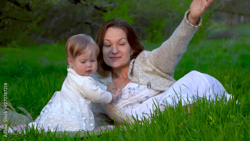 Mom and daughter are playing in the park on the grass. Happiness and harmony in family life. 4K