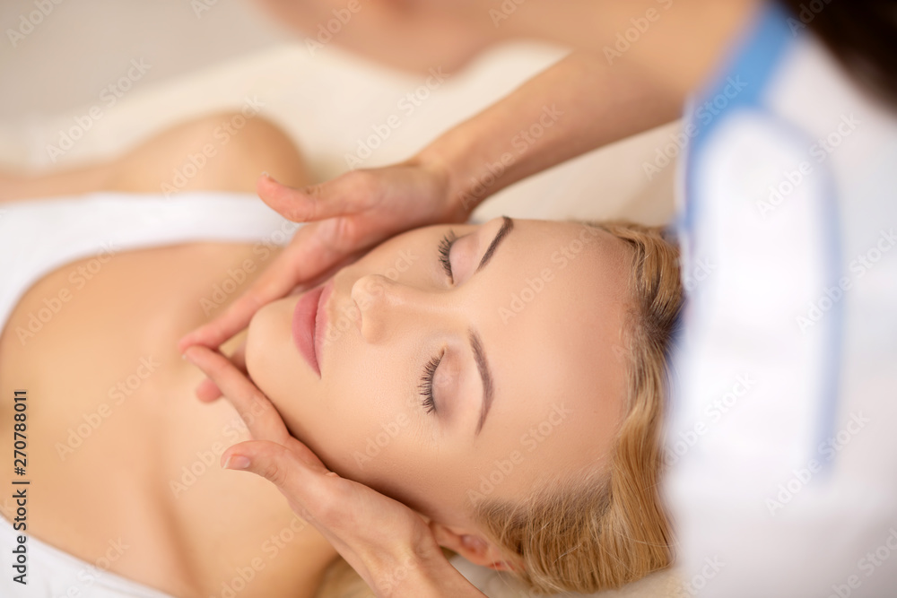 Woman closing her eyes while enjoying face massage