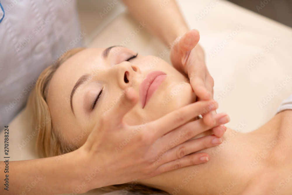 Close up of businesswoman closing eyes enjoying face massage Close up of businesswoman closing eyes enjoying face massage