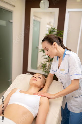 Woman wearing white top lying and having nice body massage