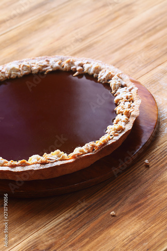 Classic Chocolate Tart on a wooden board, on wooden background.