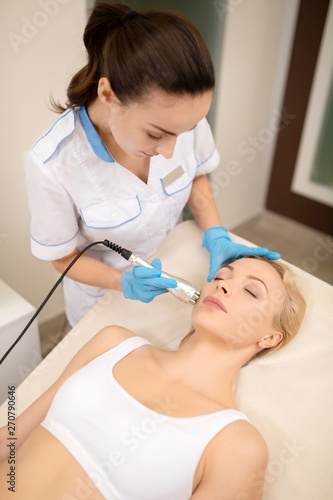 Blonde client lying and closing eyes during laser skin treatment