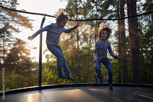 Sweet preteen boy jumping on trampoline making somersaults in the air. Happy child jumping on sunset, making different shapes