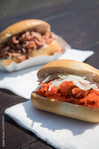 Fischbrötchen mit Nordseekrabben und Alaska Seelachs draußen auf Fischmarkt Holztisch als schneller regionaler Imbiss photo