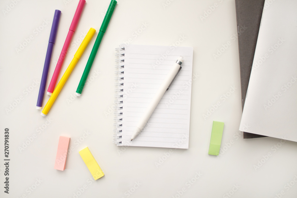 white notebook with springs sheets in line on a white background with a white pen markers colored stickers lying next to notebooks white notebook with springs sheets in line on a white background with a white pen markers colored stickers lying next to notebooks