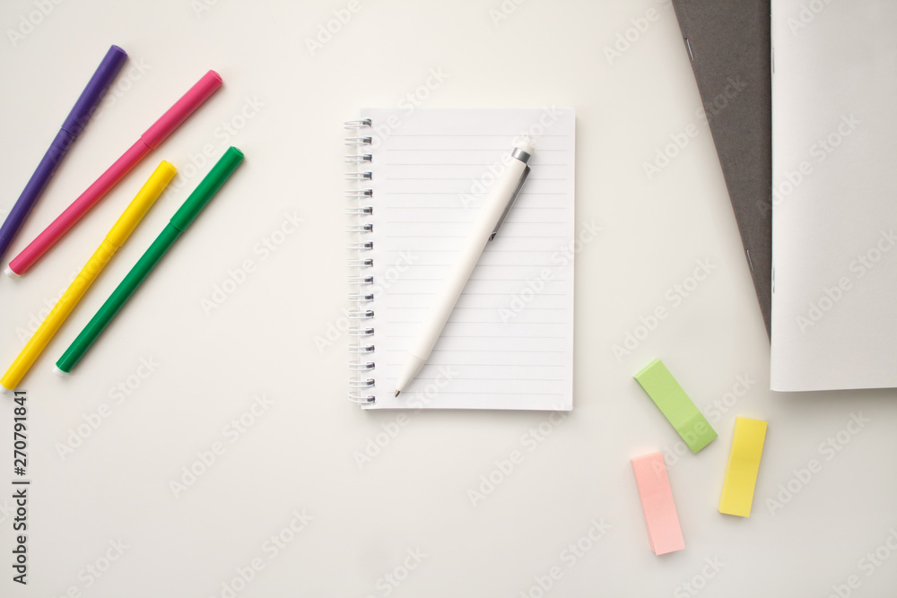 white notebook with springs sheets in line on a white background with a white pen markers colored stickers lying next to notebooks white notebook with springs sheets in line on a white background with a white pen markers colored stickers lying next to notebooks