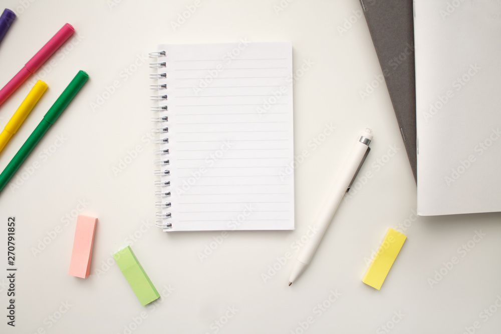 white notebook with springs sheets in line on a white background with a white pen markers colored stickers lying next to notebooks white notebook with springs sheets in line on a white background with a white pen markers colored stickers lying next to notebooks