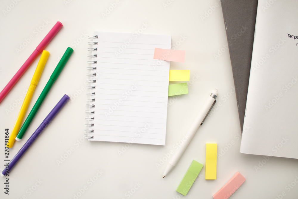 white notebook with springs sheets in line on a white background with a white pen markers colored stickers lying next to notebooks white notebook with springs sheets in line on a white background with a white pen markers colored stickers lying next to notebooks