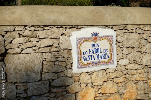Straßenschild aus Azulejos an einer Steinmauer in Cascais