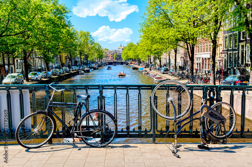 Fototapeta Naklejka Na Ścianę i Meble -  Old bicycle on the bridge in Amsterdam, Netherlands against a canal during summer sunny day. Amsterdam postcard iconic view. Tourism concept.