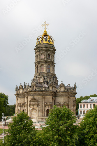 Beautiful Orthodox Christian church in the village Dubrovitsy Russia. Znamenskaya church with a single golden dome, many stone sculptures on the facade. Christian historical architecture shrine