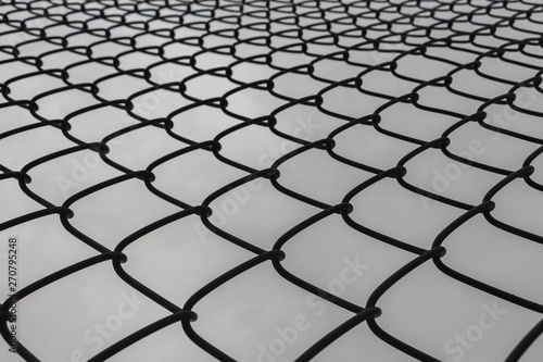 Looking Looking up at the protective metal fence and iron mesh outside the city sports fieldup at the protective metal fence and iron mesh outside the city sports field