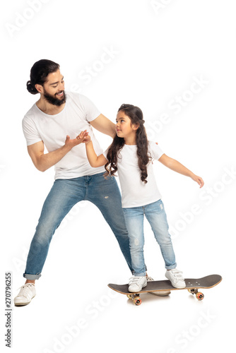 latin father holding hands with cute daughter riding penny board isolated on white