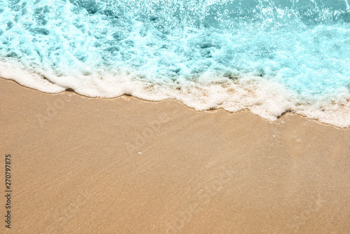 Soft wave of turquoise sea water on the sandy beach. © 26max
