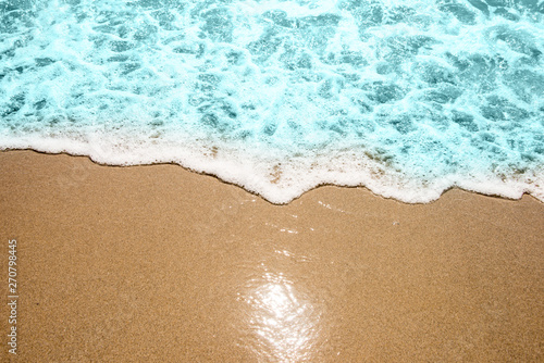 Soft wave of turquoise sea water on the sandy beach.