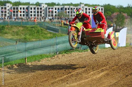 Sidecar motocross athletes jumping on the dirt track  photo