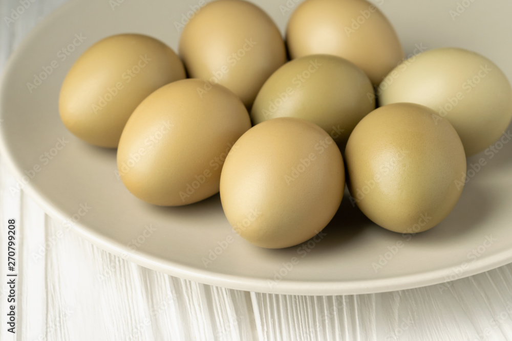 Pheasant eggs in a plate closeup on a white wooden table front view Pheasant eggs in a plate closeup on a white wooden table front view