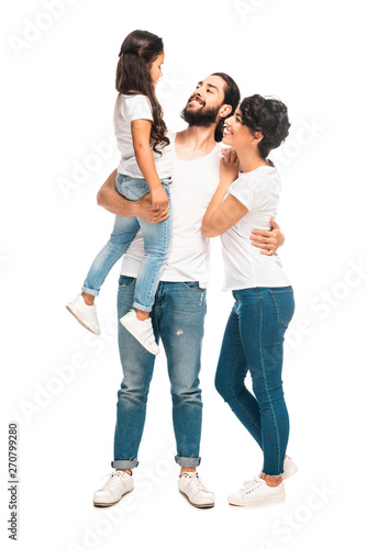 happy latin man holding in arms cute daughter while standing with attractive wife isolated on white