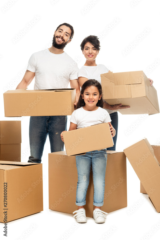 cheerful latin parents holding boxes and standing with cute daughter isolated on white cheerful latin parents holding boxes and standing with cute daughter isolated on white