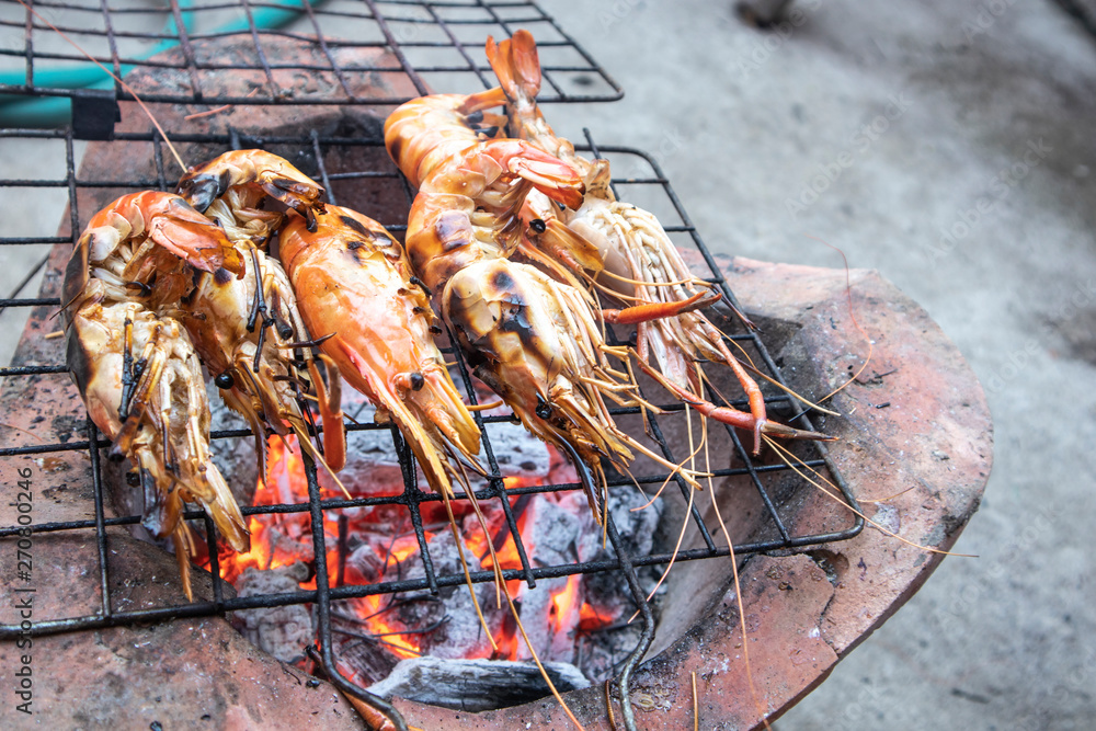 Delicious grilled prawns on flaming grill. Burnt shrimp cooking seafood on stove.