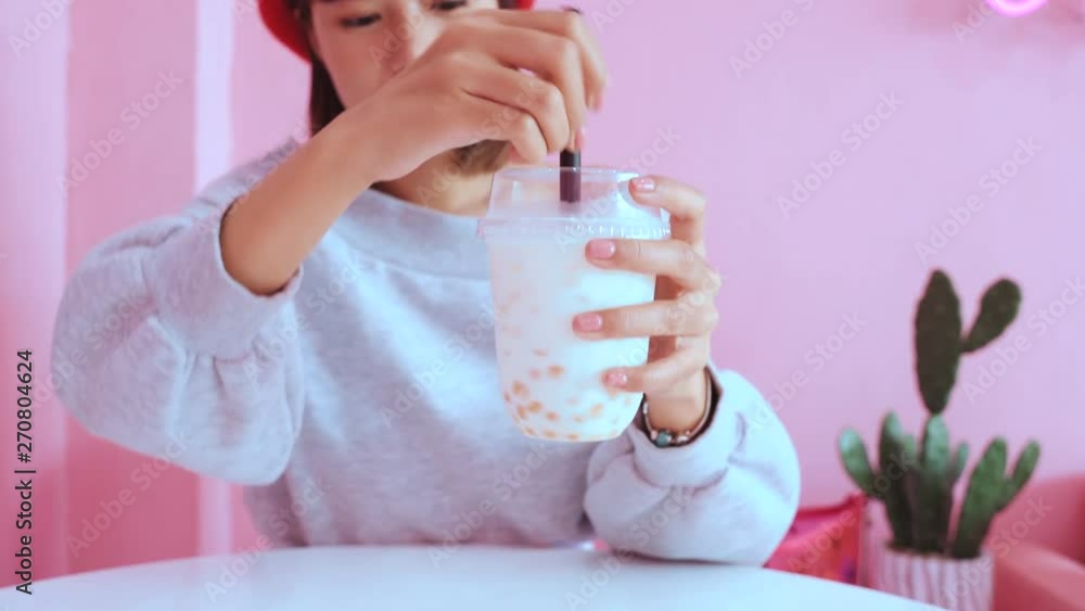 Young asian millennial woman drinking iced bubble milk tea in pink pastel cafe Young asian millennial woman drinking iced bubble milk tea in pink pastel cafe