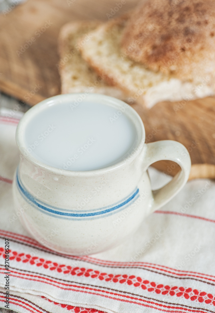 Slices of fresh wheat bread and Cup of milk on vintage tablecloth Slices of fresh wheat bread and Cup of milk on vintage tablecloth