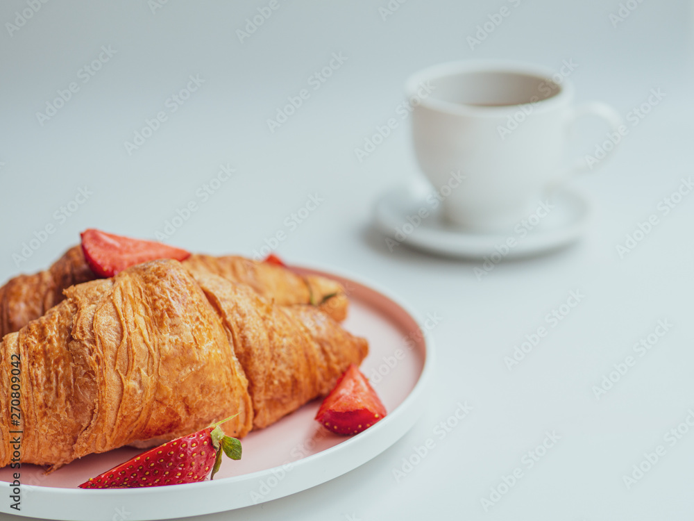 Breakfast with croissants, fresh summer strawberry, and a cup of coffee. Closeup