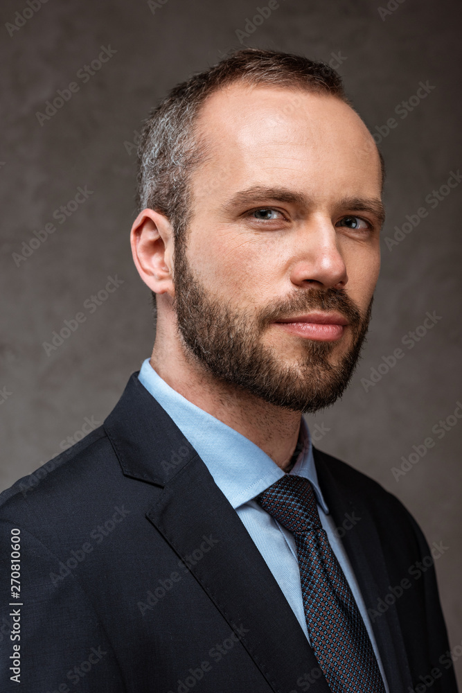 close up of confident businessman looking at camera on grey close up of confident businessman looking at camera on grey