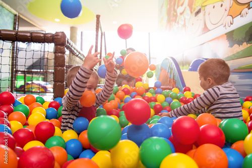 young mom playing with kids in pool with colorful balls photo