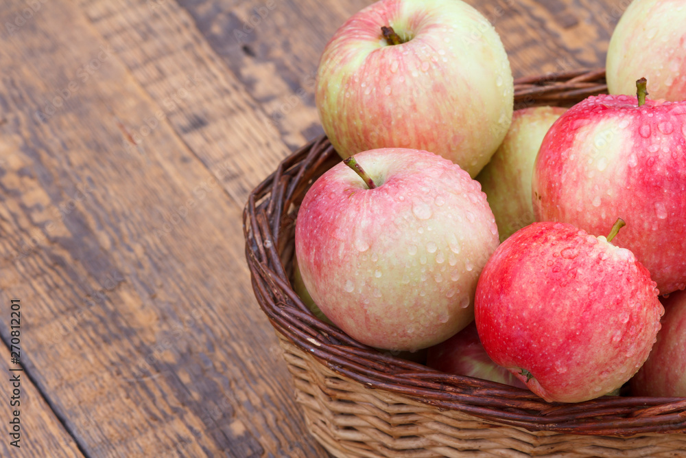 Red apples in wicker basket on old wooden boards Red apples in wicker basket on old wooden boards