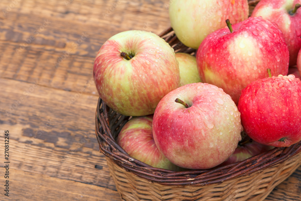 Red apples in wicker basket on old wooden boards Red apples in wicker basket on old wooden boards