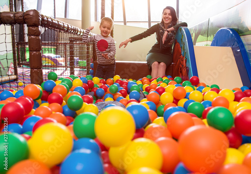 young mom playing with kids in pool with colorful balls photo