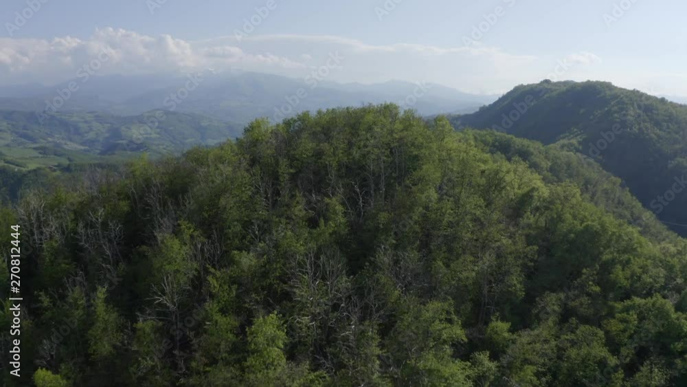 Wide angle view of drone flying over wooded hill top to show the surrounding rural countryside near Castle Carpinete in Reggio Emilia in Italy. Wide angle view of drone flying over wooded hill top to show the surrounding rural countryside near Castle Carpinete in Reggio Emilia in Italy.