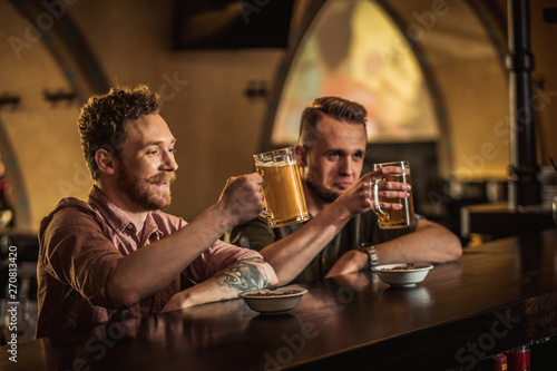 Cheerful friends drinking draft beer in a pub