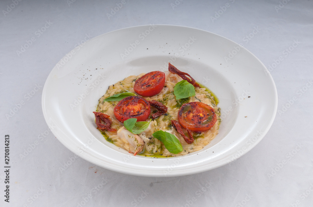 seafood risotto and dried tomatoes on a white plate on a white background seafood risotto and dried tomatoes on a white plate on a white background