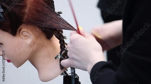 hairdresser simulates hair cutting with scissors on dummy head, practices new skills and training at hairdressing workshop, learning new profession  or refresher course, close-up view 