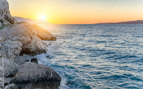 Sunset on the sea shore with rocks and pine. photo
