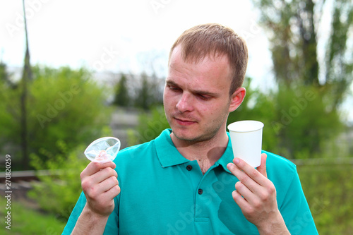 A man in a Marrs green T-shirt shows the problem of non-decomposing garbage and an alternative in the form of a paper cup. photo