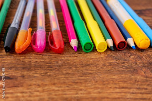 colorful pencils, markers and pens composition mock-up Back to school concept with stationery office supplies on a brown wooden background with copy space close-up